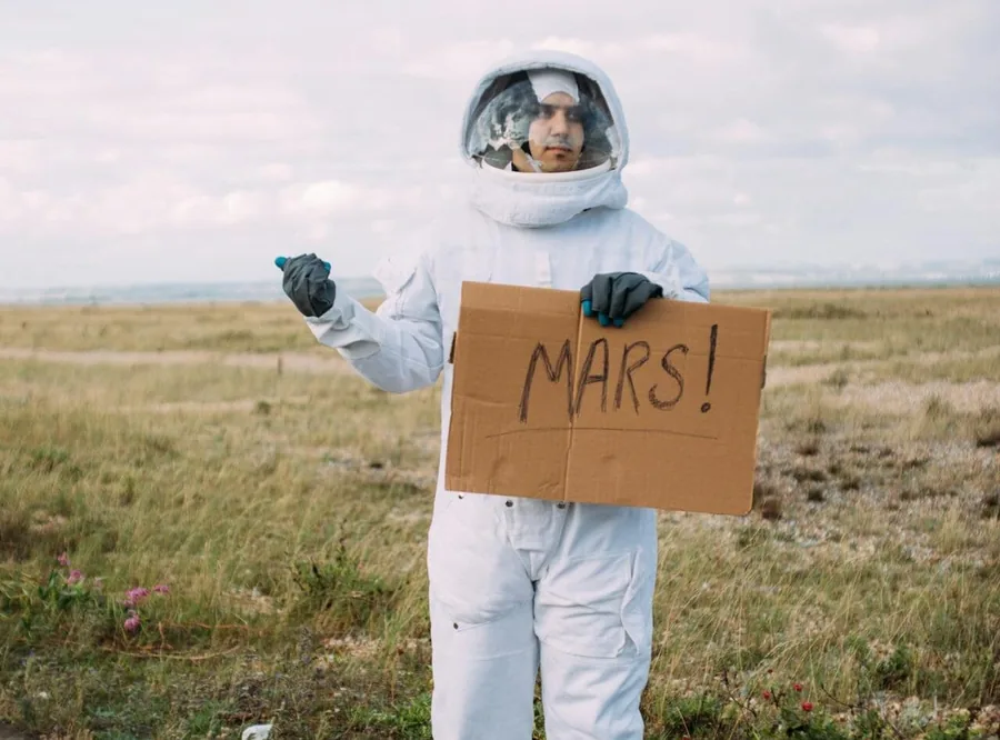 whats-next Astronautti pitää kylttiä jossa lukee MARS!